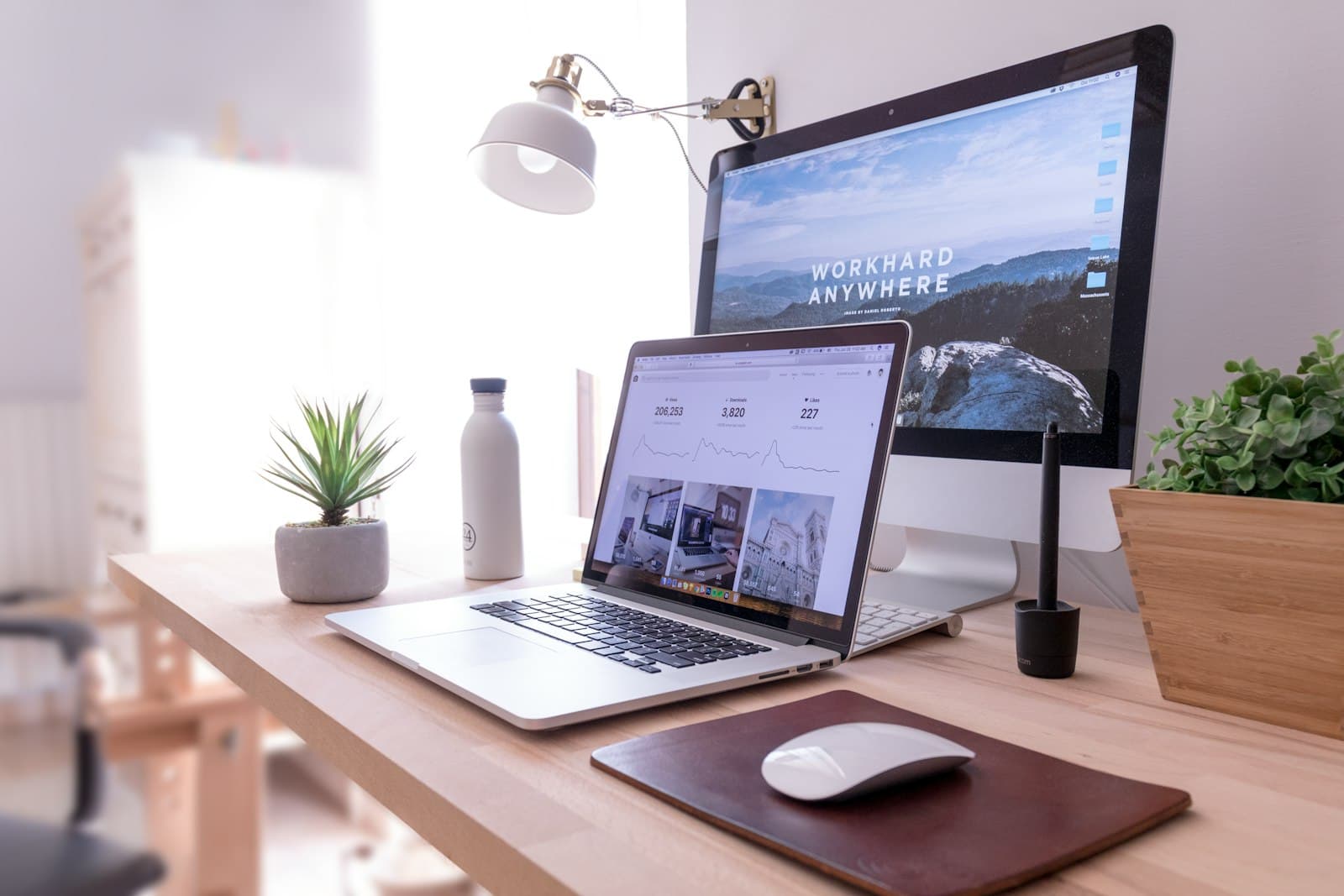 Lichte werkplek met laptop, beeldscherm en planten